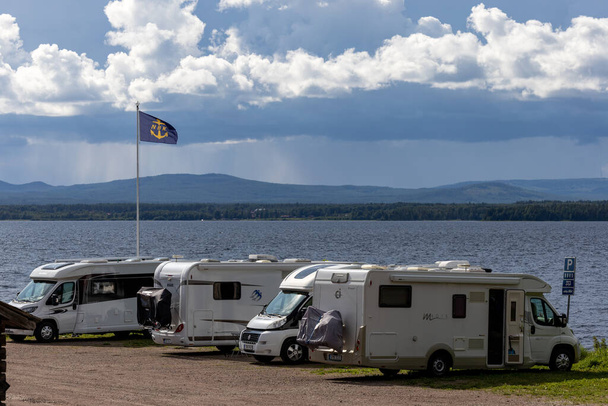 Nusnas, Sweden July 13, 2023 A row of camping vehicles parked on the shoreof Lake Siljan in the summer. - Foto, Bild