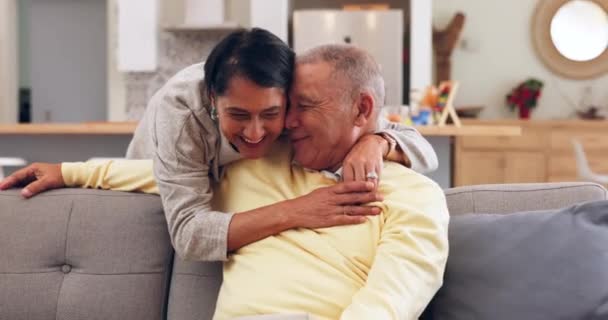 Happy, hug and senior couple on a sofa talking, bond and relax in their home together. Smile, love and old people embrace in a living room with conversation, romance and enjoy retirement or weekend. - Кадры, видео