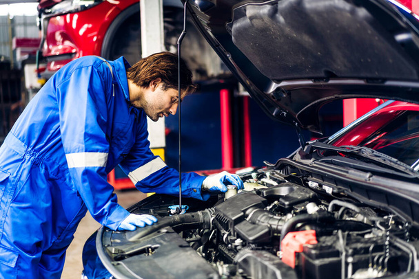 Professional car technician mechanic team in uniform work fixing vehicle car engine and maintenance repairing checking under the car hood in auto service. Automobile service garage - Photo, Image