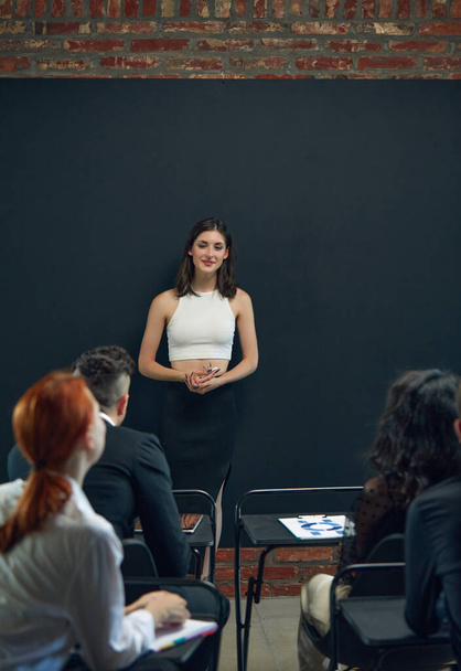 Young woman, employee, project manager standing byu blackboard and leading business meeting with colleagues. Concept of business, planning, strategy, brainstorming, teamwork, career, analytics, ad - Fotoğraf, Görsel