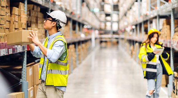 Asian two engineer team shipping order detail on tablet check goods and supplies on shelves with goods background inventory in factory warehouse.logistic industry and business export - Foto, imagen