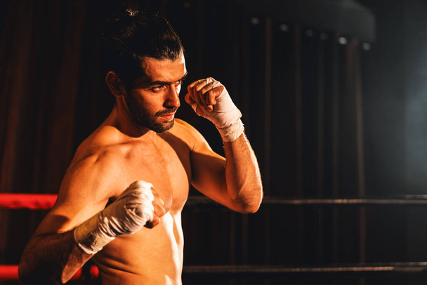 ボクシングの戦闘機の無表情なポーズ、白人ボクサーは彼の裸の拳をパンチし、カメラ、積極的なスタンスの前でラップし、ボクシングリングで戦う準備ができています。インペトゥス - 写真・画像