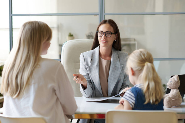 Social worker talking to single mom with child during their meeting in office - Foto, Bild