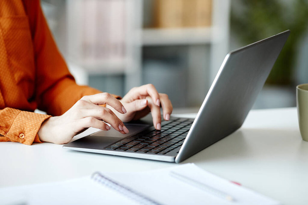 Średnie zbliżenie nierozpoznawalnej młodej kobiety pracującej w Internecie na laptopie w biurze - Zdjęcie, obraz