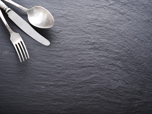 Silver cutlery on a dark grey background. - Фото, изображение