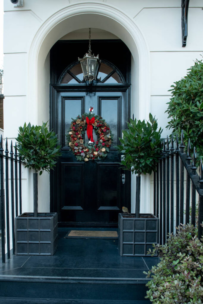 Πόρτες εισόδου σε σπίτια του Λονδίνου. Πανηγύρι διακοσμημένο για την μπροστινή πόρτα των Χριστουγέννων ενός από τα σπίτια - Φωτογραφία, εικόνα