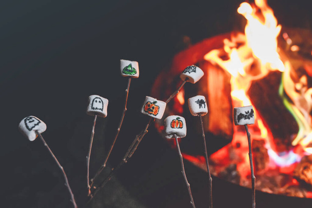 Marshmellows ze zdjęciami z Halloween nad ogniem. Zabawny wypoczynek na tradycyjnych, upiornych wakacjach dla dzieci i rodzin - Zdjęcie, obraz