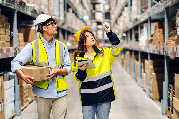Asian two engineer team shipping order detail on tablet check goods and supplies on shelves with goods background inventory in factory warehouse.logistic industry and business exportv - Фото, изображение