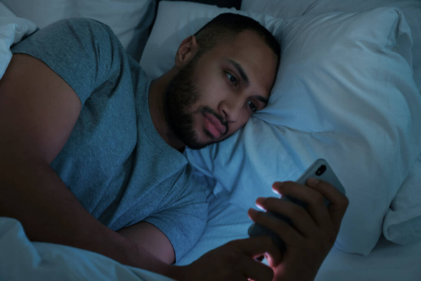 Young man using smartphone in bed at night. Internet addiction - Foto, Imagen