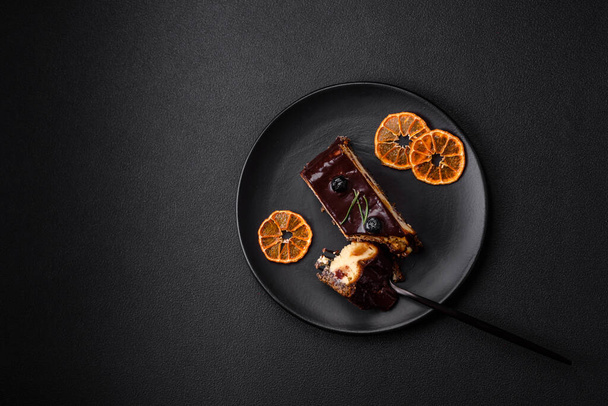 Köstlicher süßer Dessert-Käsekuchen mit kandierten Früchten in Schokolade auf dunklem Betongrund - Foto, Bild