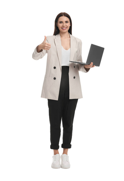 Beautiful businesswoman in suit with laptop showing thumbs up on white background - Zdjęcie, obraz