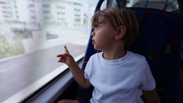 Dziecko patrząc przez okno autobusu wskazując dziecko pasażera miasta w transporcie publicznym - Zdjęcie, obraz