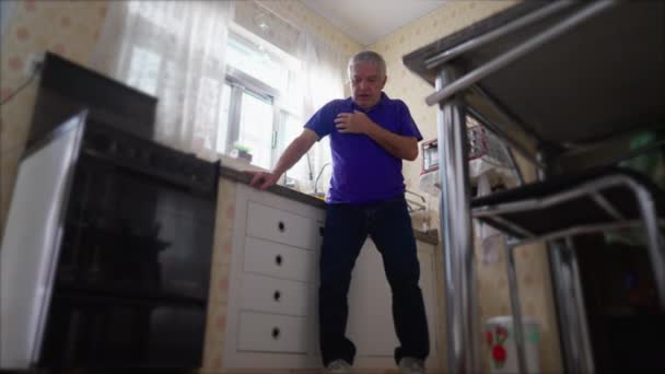 Scena di emergenza dell'uomo anziano che soffre di attacco di cuore, cadendo al pavimento dal lavandino della cucina, colpo di basso angolo della persona anziana che ha dolore cardiovascolare nel torace - Filmati, video