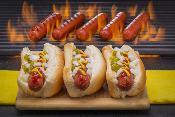 Three Delicious Hot Dogs with Grilling Barbecue Background - Photo, Image