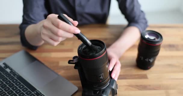 Fotógrafo limpa lente de poeira usando escova suave. Senhora com lentes profissionais para câmera fica perto do laptop. Atitude cuidadosa em relação a equipamentos caros - Filmagem, Vídeo