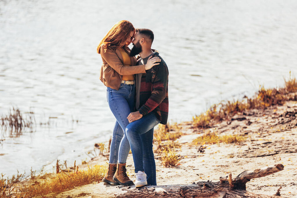 Glückliches junges verliebtes Paar hält Händchen und spaziert an der Küste in Flussnähe.  - Foto, Bild