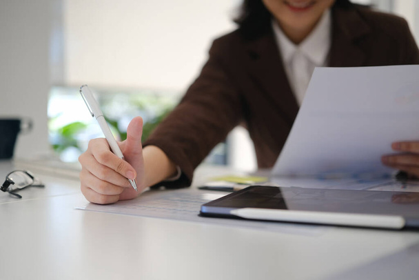 Main d'une jeune femme d'affaires écrivant sur papier, préparant un rapport économique au bureau. - Photo, image