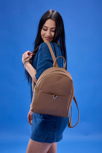 una joven morena con el pelo largo posando en el estudio con una mochila, concepto Back to school. - Foto, Imagen