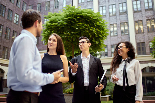 Business people, employees, colleagues standing outside office on street, lively talking. Cooperation, teamwork. Concept of business, career development, ambitions, success and office lifestyle - Foto, Imagen
