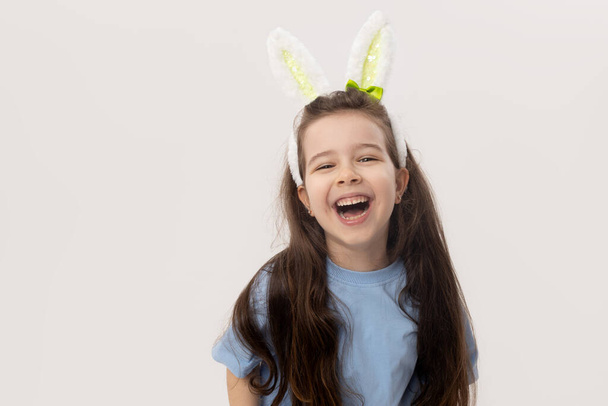 Cute little child girl with bunny ears on white background. Funny face - 写真・画像