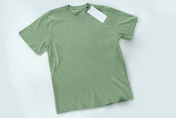 Grünes T-Shirt auf dem Tisch liegend, Ansicht von oben, Ganzkörper mit einem leeren Zeichen des Logos hängend. - Foto, Bild