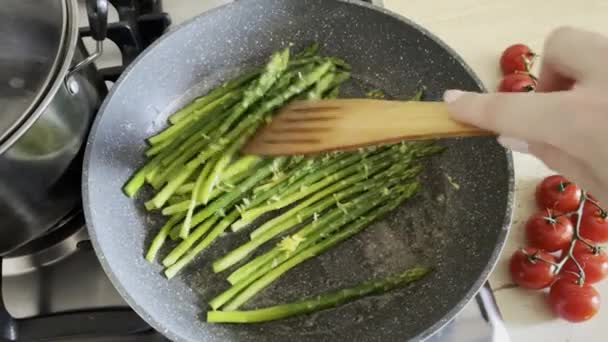 Le processus de cuisson de brins verts frais de délicieuses asperges croustillantes et saines avec du sel et des épices dans le cadre d'un plat végétarien - Séquence, vidéo
