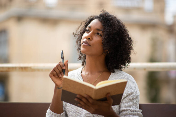 Retrato jovem afro-americana pensando enquanto escrevia no livro - Foto, Imagem