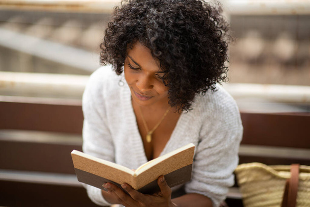 close up portret jong Afrikaans amerikaans vrouw voorlezen boek buiten - Foto, afbeelding