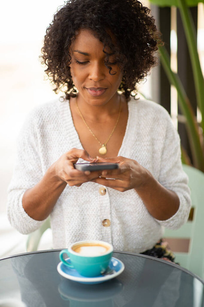 Retrato de mujer joven tomando fotografías con teléfono móvil de taza de café - Foto, imagen