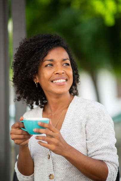 Gros plan portrait jeune femme afro-américaine tenant du café à l'extérieur - Photo, image