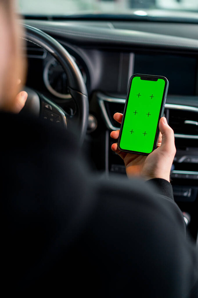 Muž sedí v luxusním autě se zeleným displejem v ruce - Fotografie, Obrázek