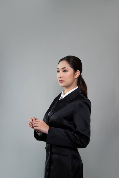 Впевнена молода бізнес-леді стоїть на ізольованому фоні, позуючи в офіційному чорному костюмі. Офісна леді або менеджер з розумною та професійною зовнішністю. Ентузіазм
 - Фото, зображення
