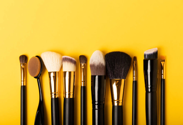 Cosmetic makeup brush on a yellow background. Cosmetic product for make-up. Creative and beauty fashion concept. Fashion. Collection of cosmetic makeup brushes, top view, banner.Place for text.  - Photo, Image