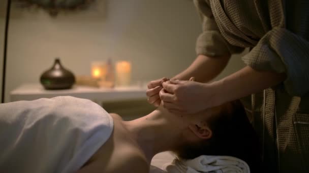 Vídeo de massagem. Uma massagista dá a uma mulher um pescoço e uma massagem na cabeça em um ambiente calmo e relaxante. Mulher relaxada deitada no sofá com os olhos fechados em um salão de spa. Massagem de corpo inteiro - Filmagem, Vídeo