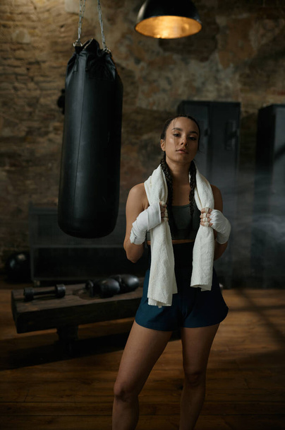 Satisfied woman boxer with towel on shoulders looking at camera. Sport, hobby and personal achievement concept - Foto, imagen
