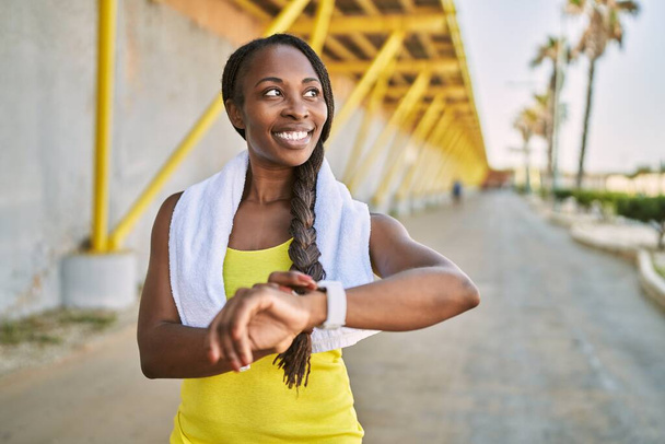 Αφροαμερικανή γυναίκα που φοράει αθλητικά ρούχα που μοιάζουν με χρονόμετρο στο δρόμο - Φωτογραφία, εικόνα