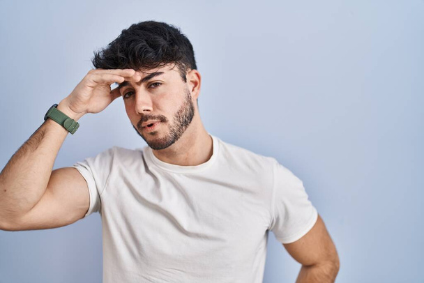 Hispanic man with beard standing over white background worried and stressed about a problem with hand on forehead, nervous and anxious for crisis  - Photo, image