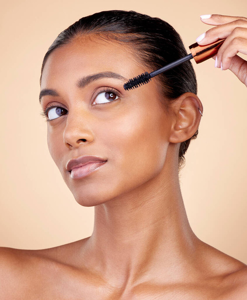 Face, mascara brush and woman, beauty and makeup with cosmetics tools isolated on studio background. Indian female model, cosmetology and skin glow, shine and eyelash extension with wellness. - Φωτογραφία, εικόνα