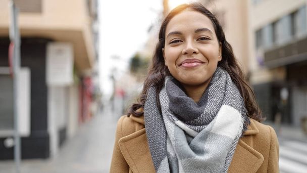Jonge mooie Spaanse vrouw glimlachend vol vertrouwen op straat - Foto, afbeelding