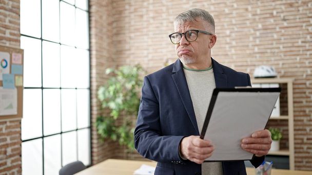 Homem de cabelos grisalhos de meia idade empresário segurando checklist no escritório - Foto, Imagem