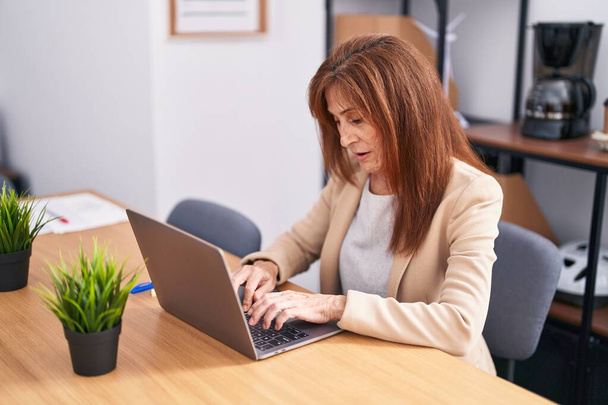 Middle age woman business worker using laptop working at office - Foto, afbeelding