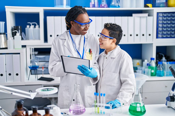 Cientistas afro-americanos de mãe e filho sorrindo confiantes medindo laboratório líquido - Foto, Imagem