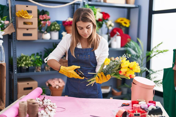 Młoda kobieta kwiaciarnia zrobić bukiet kwiatów cięcia nożyczkami w kwiaciarni - Zdjęcie, obraz