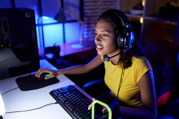 Молода афроамериканська жінка стрімер грає у відеоігри за допомогою комп "ютера в ігровій кімнаті. - Фото, зображення