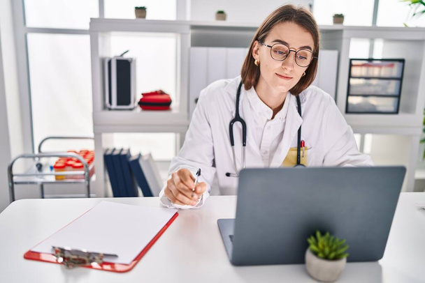 Young caucasian woman doctor using laptop working at clinic - Zdjęcie, obraz