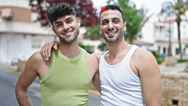 Двоє чоловіків посміхаються впевнено обіймаючи один одного на вулиці
 - Фото, зображення