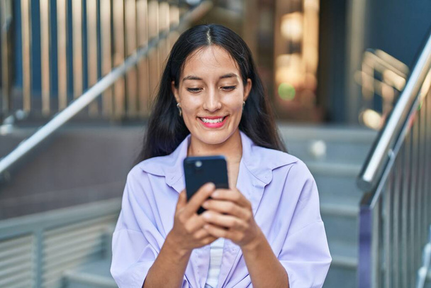 Young beautiful hispanic woman smiling confident using smartphone at street - Foto, Imagen
