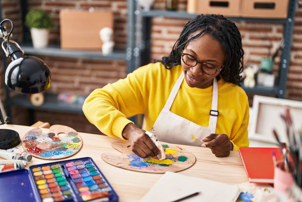 Mujer afroamericana artista sonriendo confiado mezcla de color en el estudio de arte - Foto, imagen