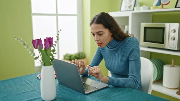 Young beautiful hispanic woman using laptop sitting on table at home - Fotoğraf, Görsel