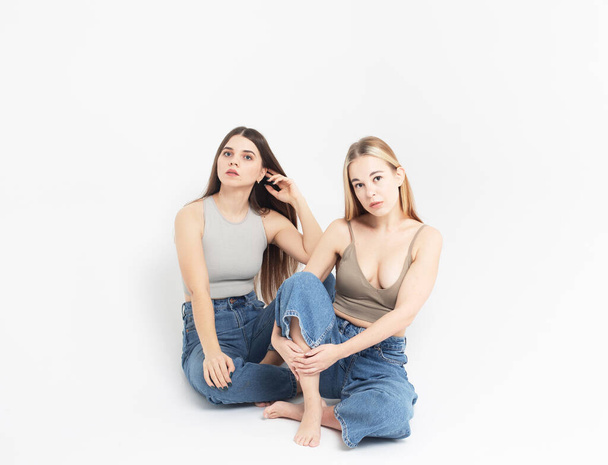 životní styl a lidé koncept: Dvě mladé přítelkyně sedí na podlaze spolu. - Fotografie, Obrázek